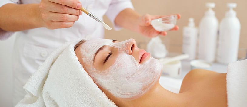 Esthetician applying a face mask to a female client.