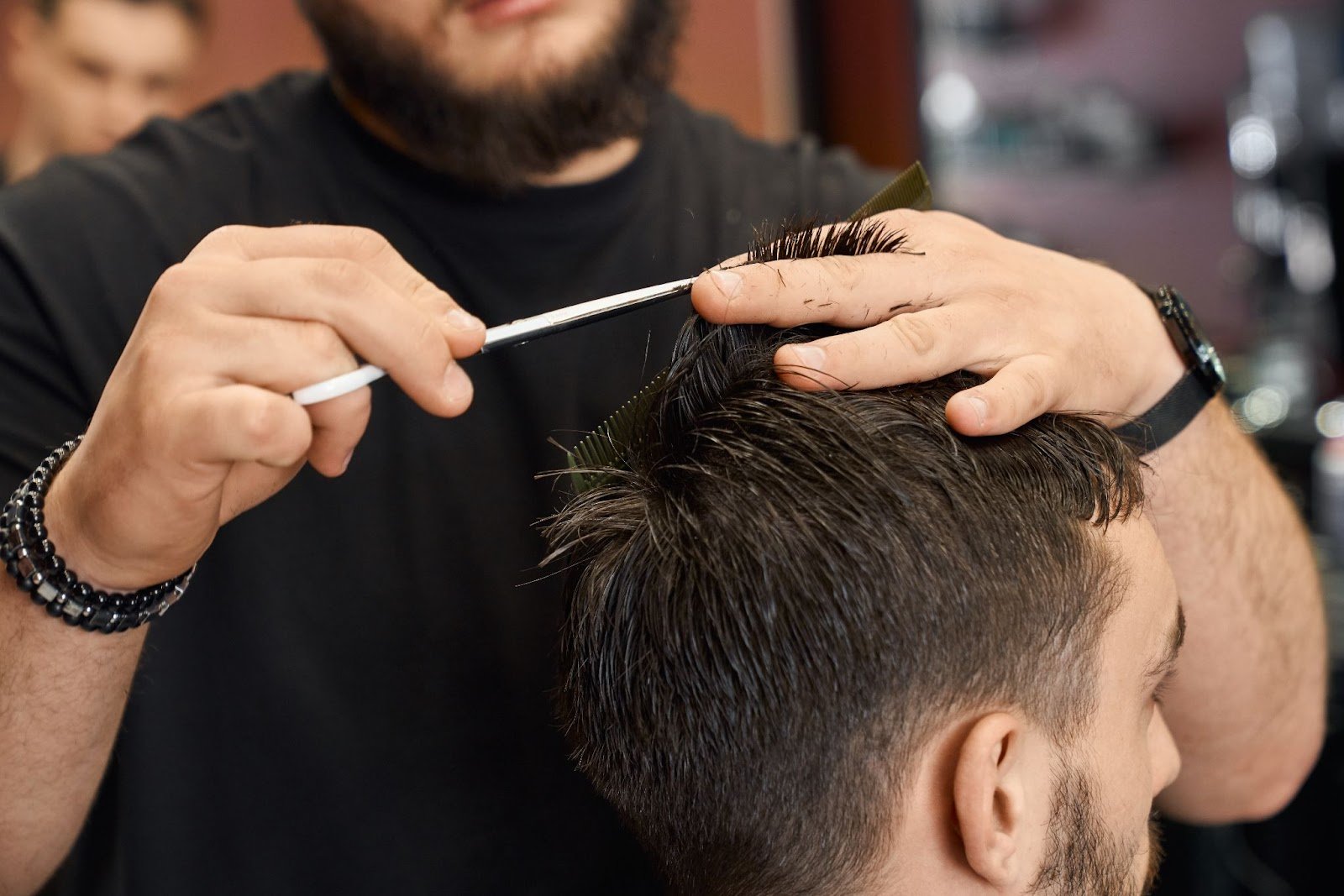 Top Tips on Cutting Men’s Hair: A Guide for Beginners & Future Barbers 7 Barber using scissors and comb to cut a client’s hair in a professional barbershop