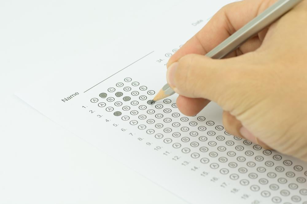 Cosmetology State Board Exam: How to Prepare 2 Close-up of hand filling out a multiple-choice answer sheet during an exam