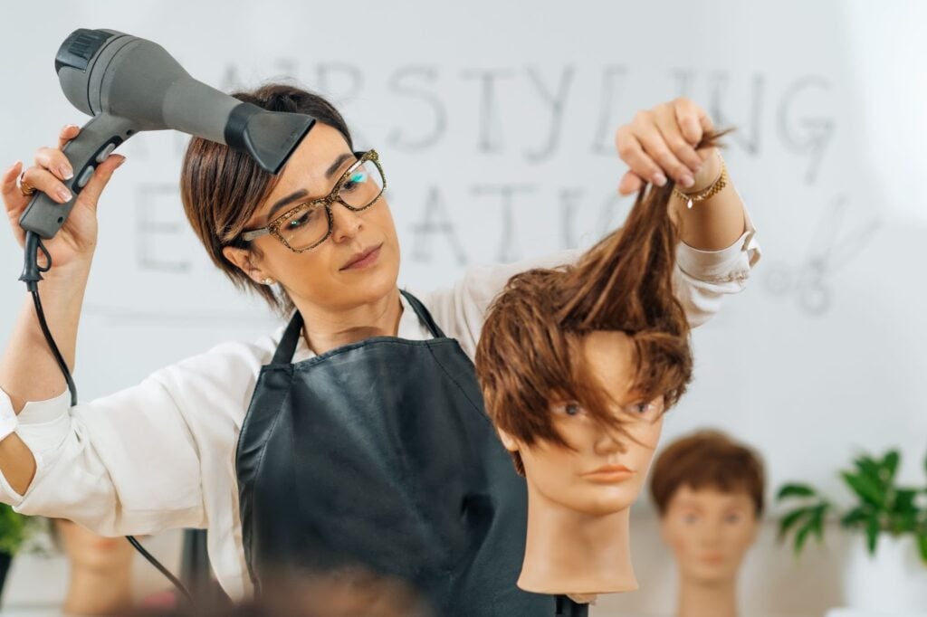 Cosmetology student practicing haircutting techniques on a mannequin at Cosmetology & Spa Academy