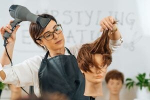 Cosmetology student practicing haircutting techniques on a mannequin at Cosmetology & Spa Academy