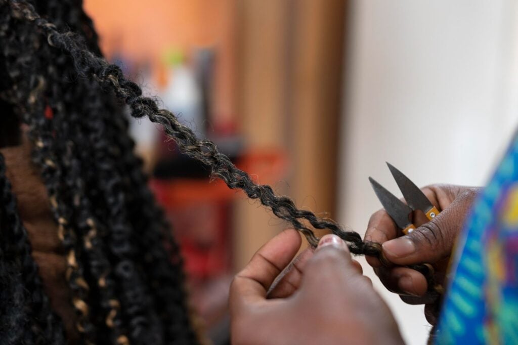 Close-up of hands cutting a strand of twisted hair with scissors in a hair salon.