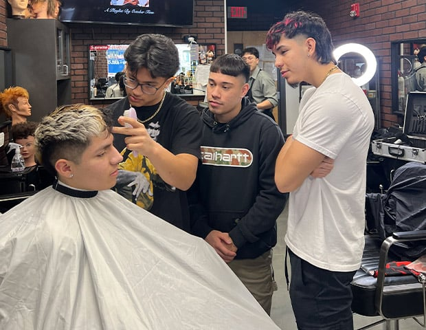 Group of aspiring hairstylists practicing coloring techniques in a professional classroom environment.