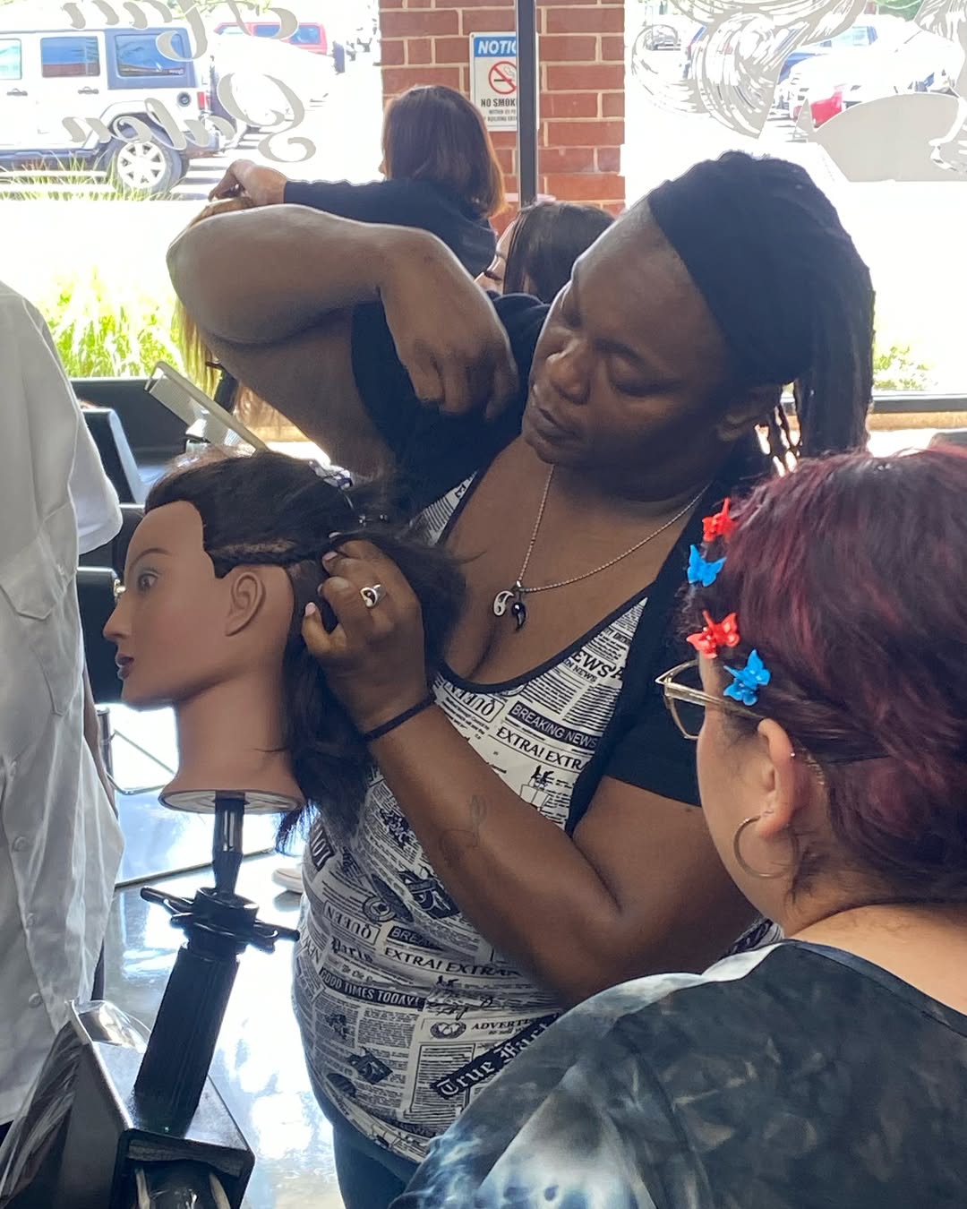 How To Braid African Hair: A Guide for New Cosmetologists 3 Instructor demonstrating braiding techniques on a mannequin head while students observe during a cosmetology class.