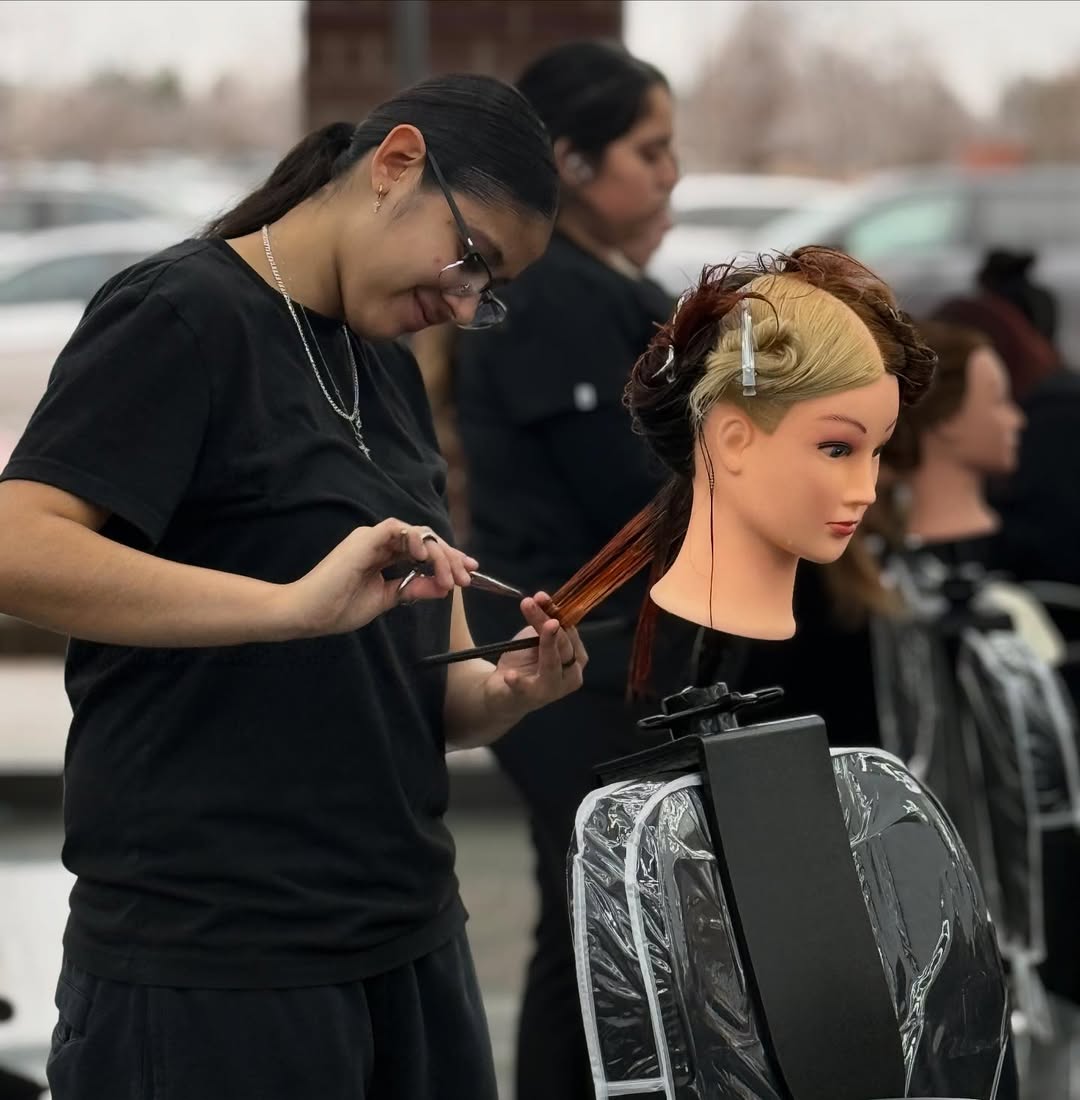 How to Choose a Beauty School: Making The Right Decision 6 Cosmetology student practicing haircutting techniques on a mannequin head during beauty school training.