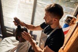Student styling hair at barber training at academy.
