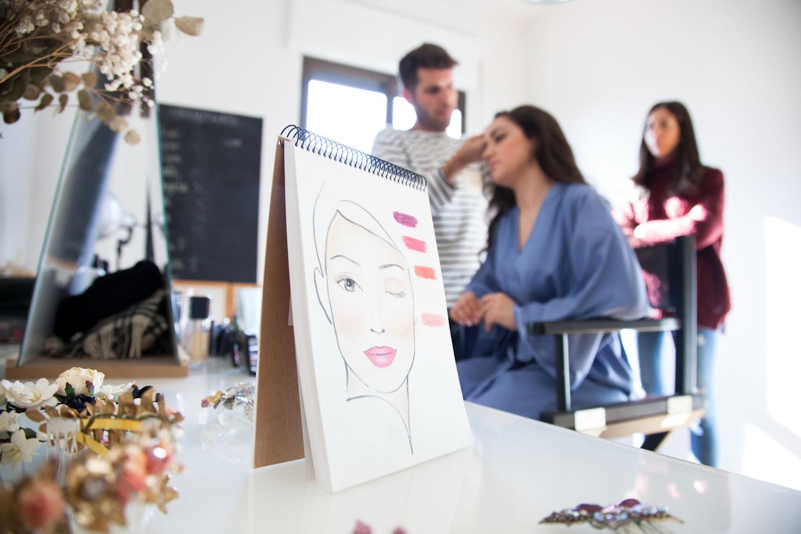 Cosmetology State Board Exam: How to Prepare 1 Makeup sketch on easel with beauty professionals preparing client in background