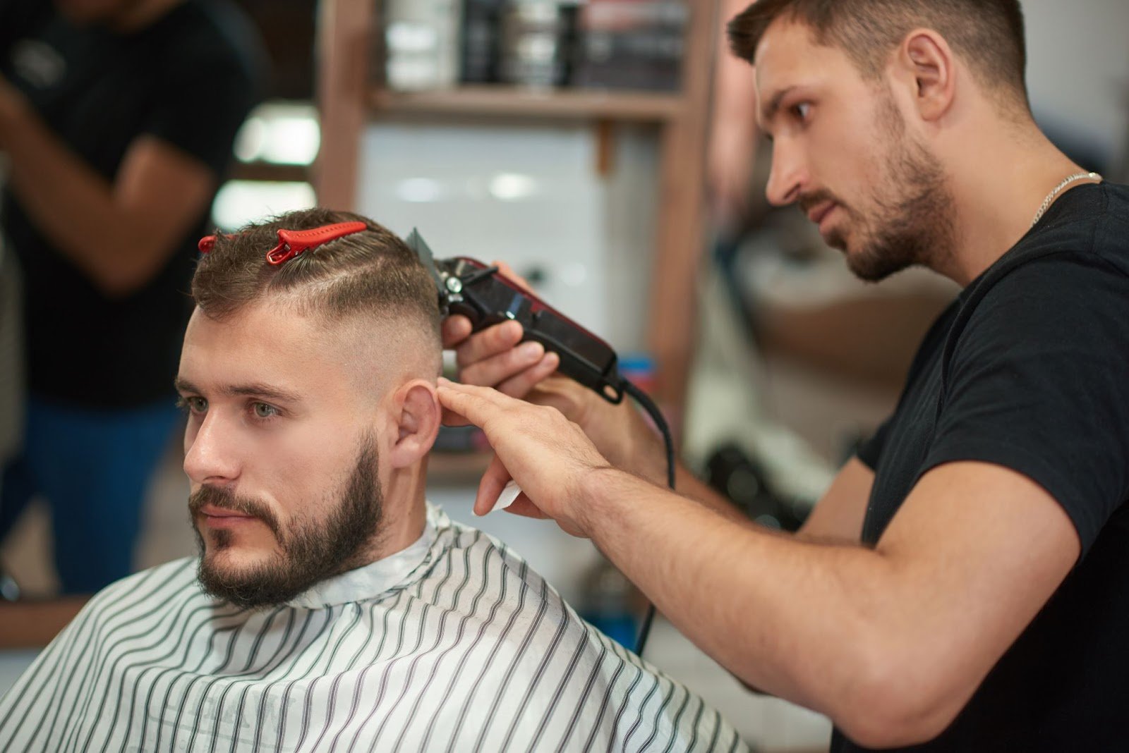 Top Tips on Cutting Men’s Hair: A Guide for Beginners & Future Barbers 3 Barber giving a modern fade haircut to a male client in a professional barbershop