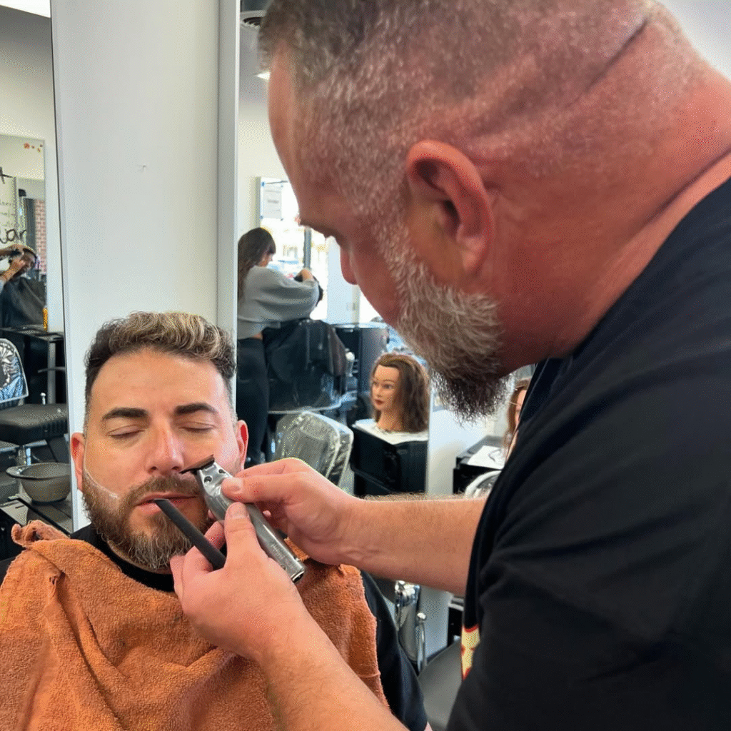 Top Actors Who Have Played Barbers in Hollywood Movies 6 Professional barber shaping client’s beard with clippers in barbershop
