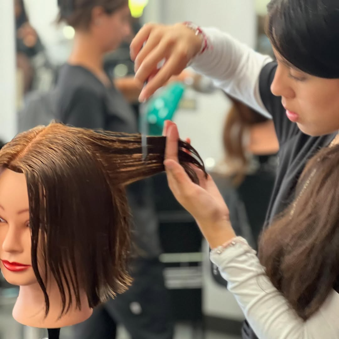 Beauty school student practicing haircutting techniques on mannequin head