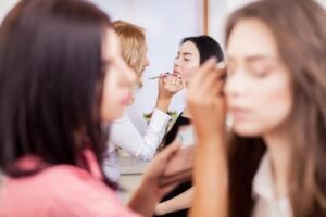 Students at a cosmetology school applying makeup in a salon.