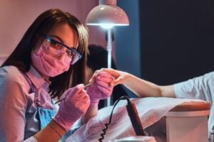 Nail school student applying acrylic nails on a client.