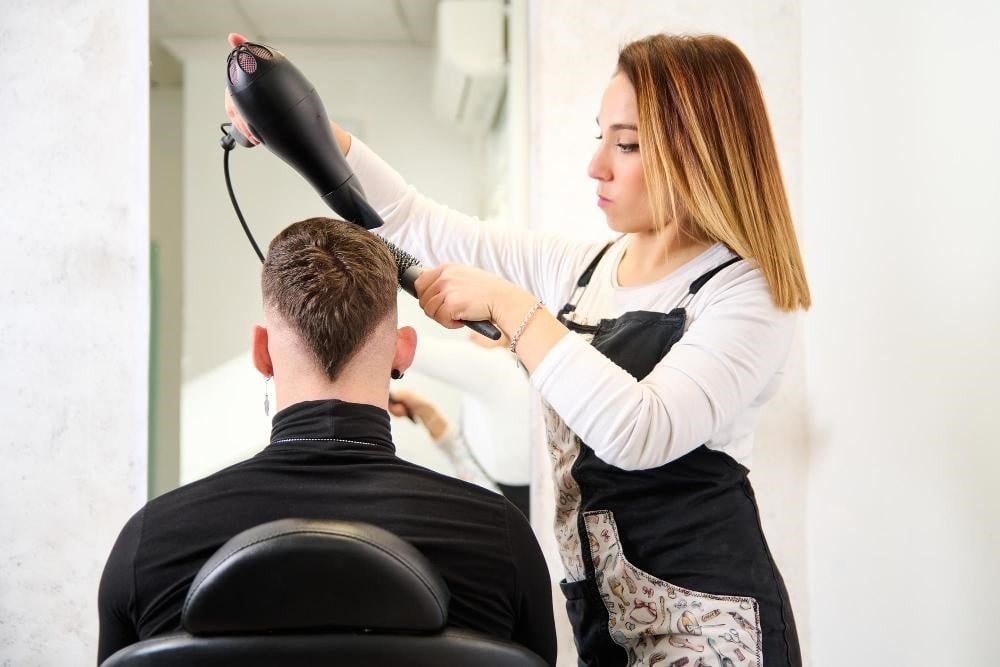 Hair school student styling a male client's hair.