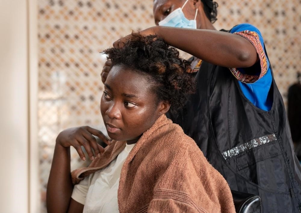 Cosmetology student braiding textured hair.