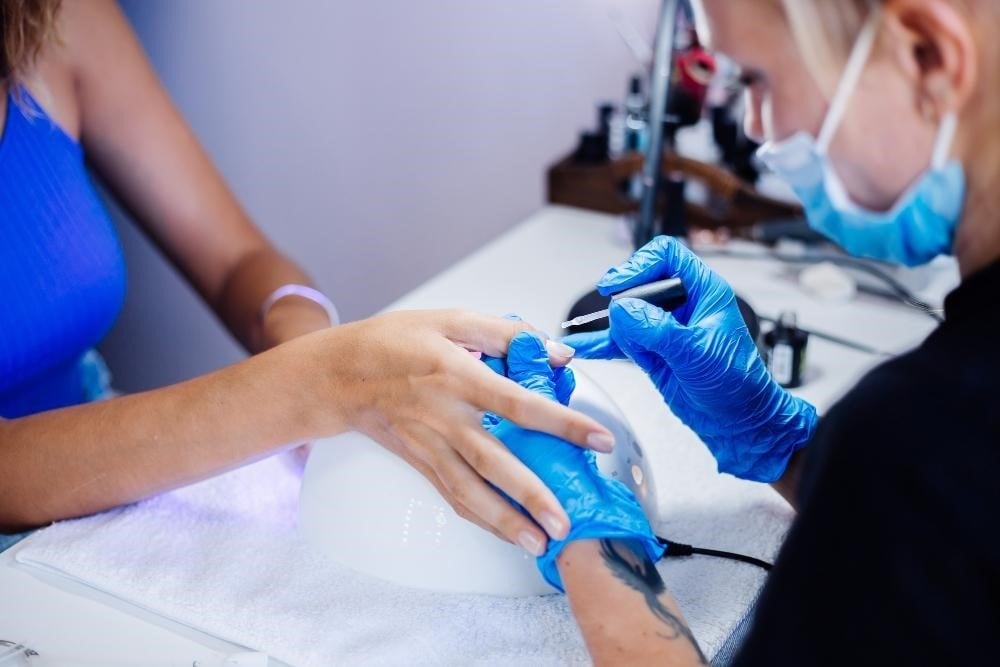 Nail technician working on a client's manicure. 