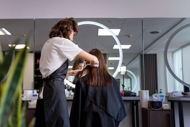 Student at a cosmetology school in Illinois practicing different hair cutting techniques on a client