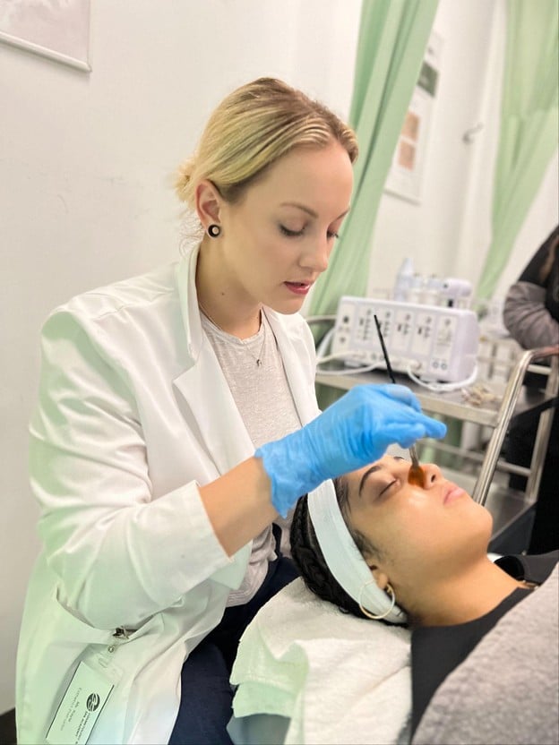 Esthetics student applying professional skincare treatment during hands-on training at Cosmetology & Spa Academy in Illinois.