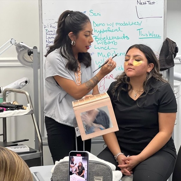 Esthetics students practicing professional skincare and makeup application during hands-on training at Cosmetology & Spa Academy in Illinois.
