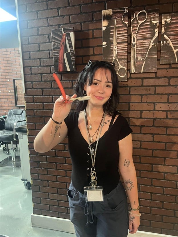 Barbering student practicing straight razor techniques during hands-on training at Cosmetology & Spa Academy, a barber school in Illinois.