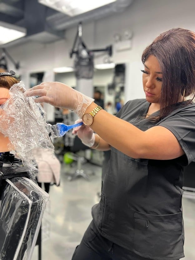 Cosmetology instructor demonstrating professional hair coloring and blending techniques to students at an Illinois beauty school