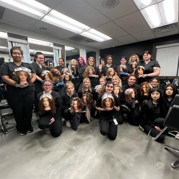 Cosmetology students posing with mannequin heads after completing color and ombre hair training at Cosmetology & Spa Academy beauty school in Illinois.
