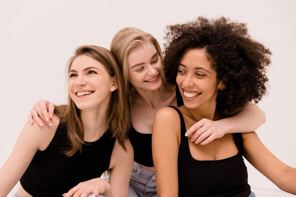 Diverse women with different hair textures smiling together representing natural hair diversity in cosmetology.