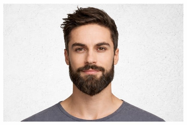 Male model with medium full beard and textured hairstyle representing a popular modern beard style.