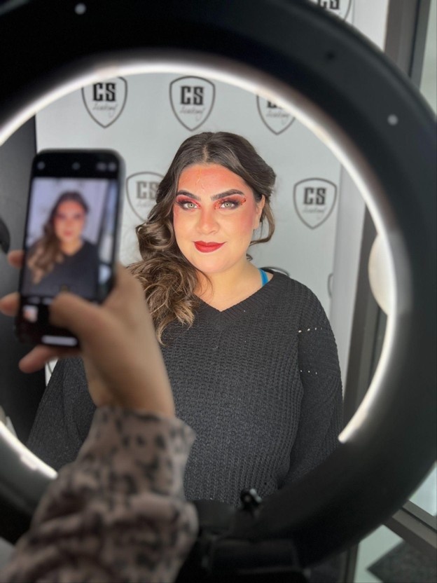 Makeup artist photographing a finished makeup look with a ring light for a professional makeup artist portfolio.