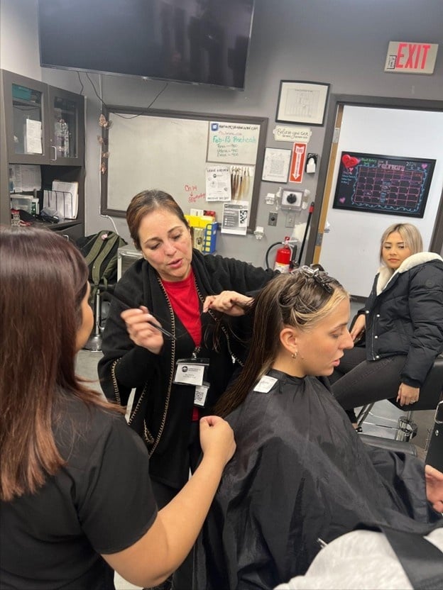 Cosmetology student practicing hairstyling techniques on a client during beauty school training.