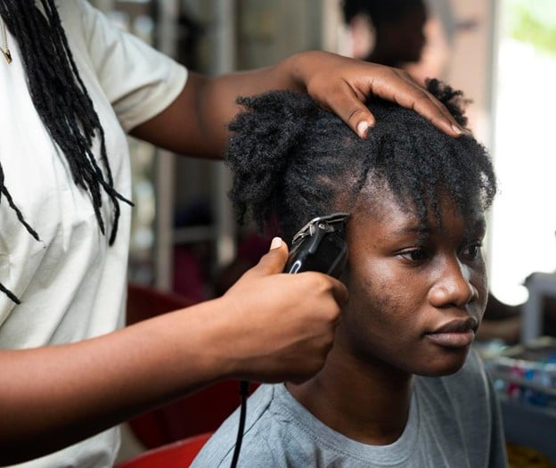 student practicing African hair cutting techniques at Cosmetology & Spa Academy, one of the best hair schools in Illinois